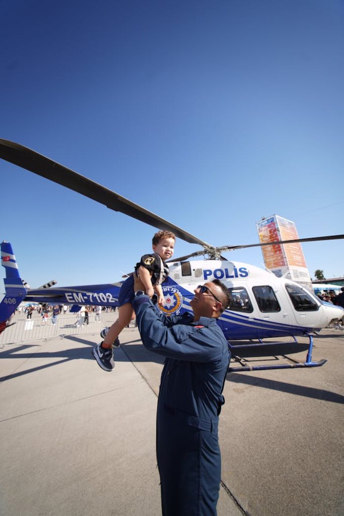 police-officer-lifts-child-by-helicopter-at-airshow-28801193 A police officer lifts a child near a helicopter at an outdoor event in Adana, Turkey.